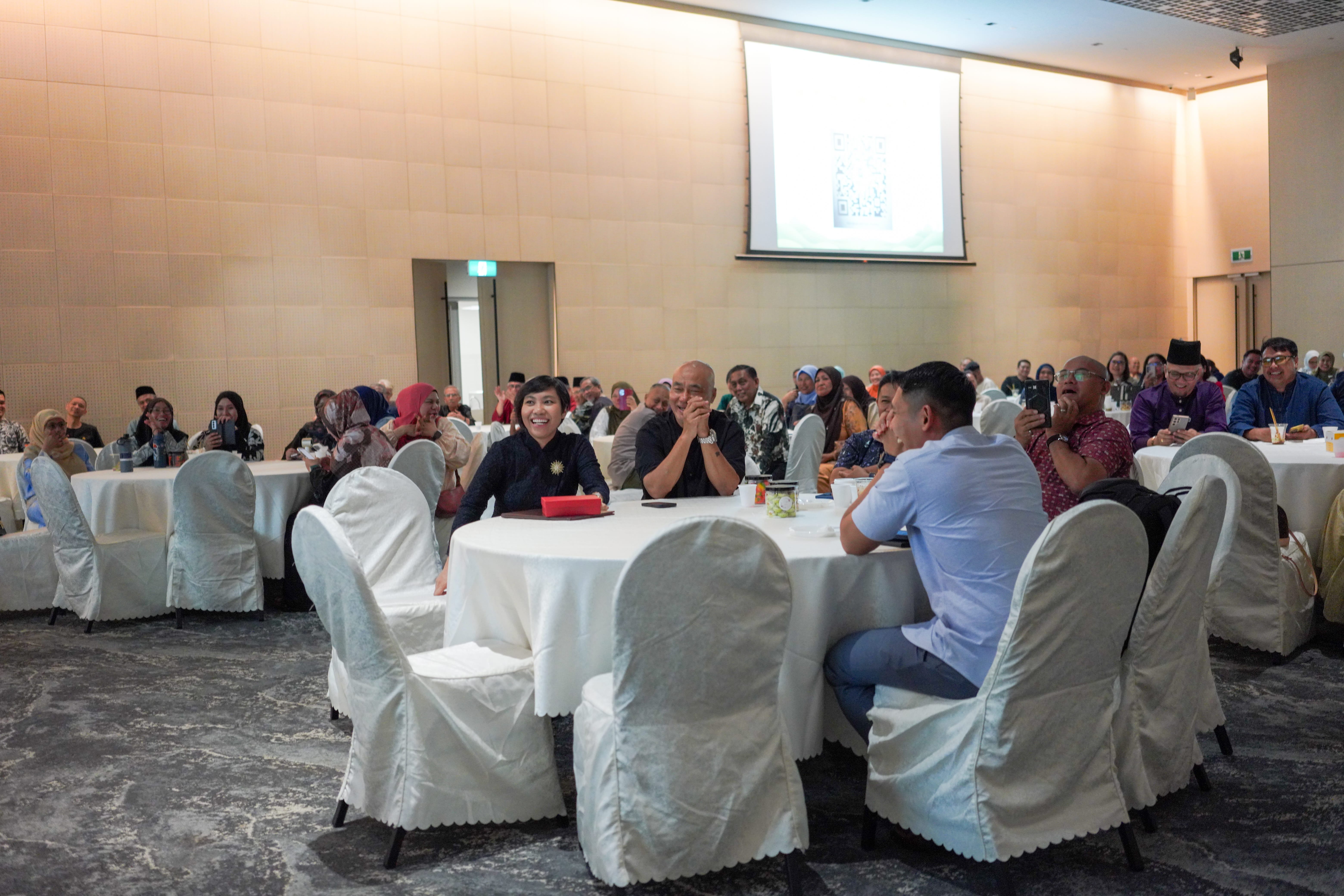 Guests gathered around banquet tables watching a stage performance and sharing a light-hearted moment.